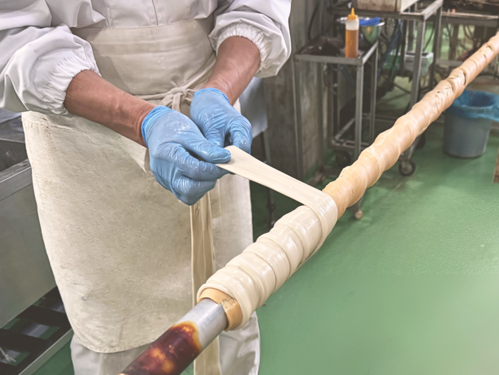 棒に生地を巻き付けて成形する工程。車麩など焼き麩特有の形をつくる作業。
