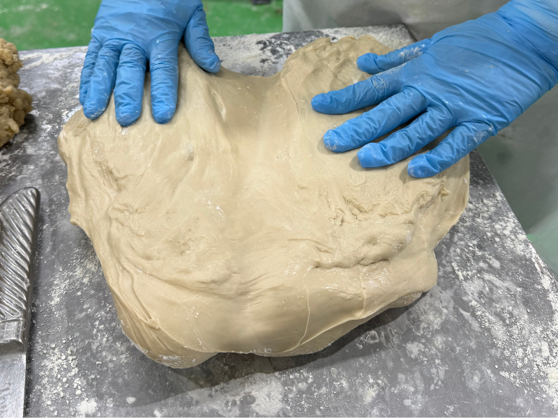 お麩の生地を手作業で整える工程。水分や状態を確認しながら調整する作業。
